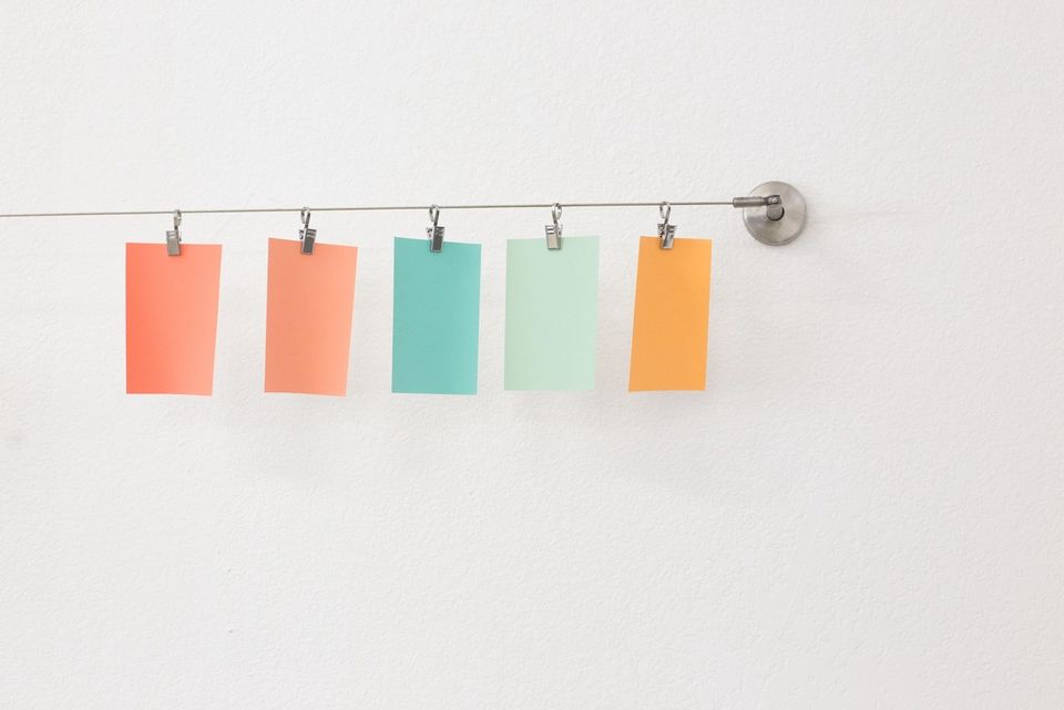 Colourful blank postit notes hanging on a line suspended from clips. They look like laundry.